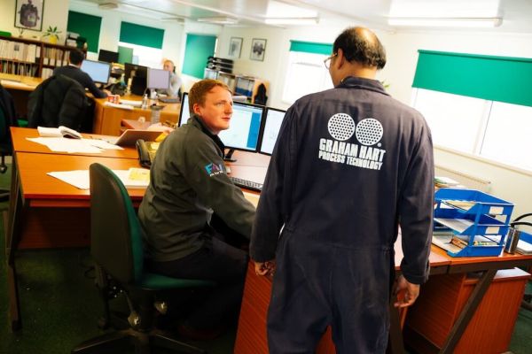 Mechanical Engineer talking to a fabricator in Graham Hart overalls